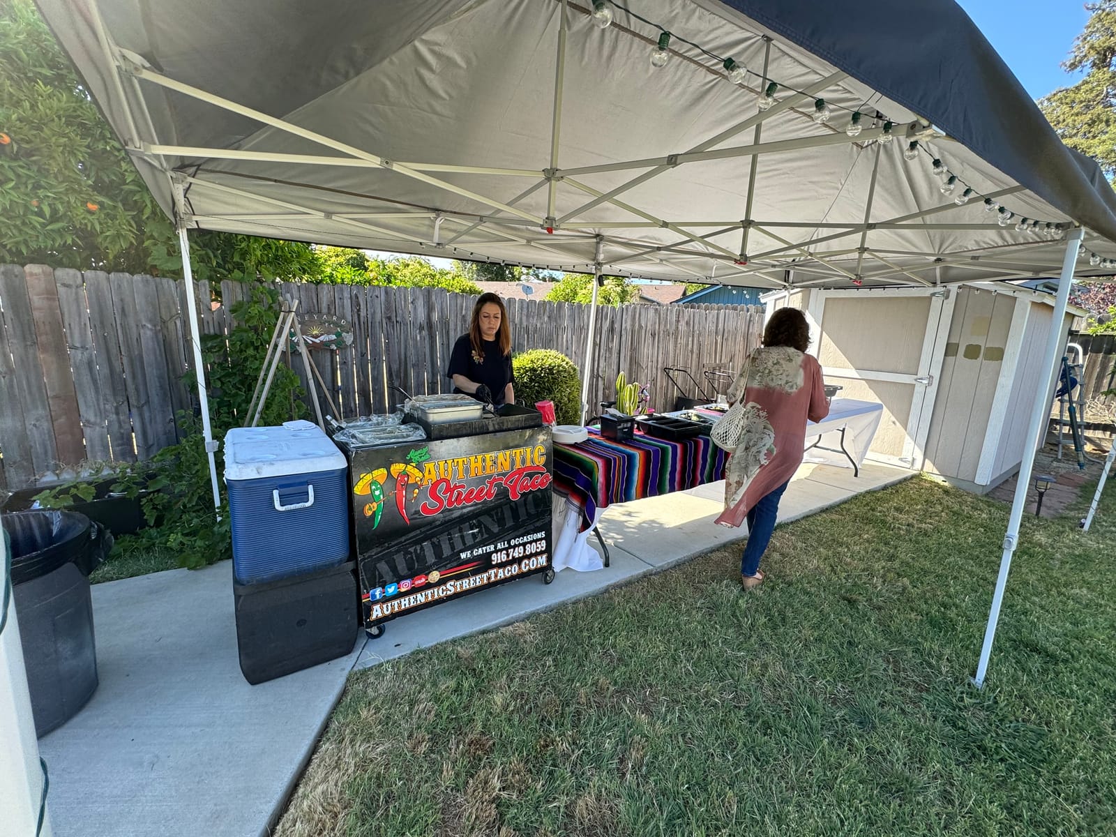 Taco grill station set up under a canopy in a backyard